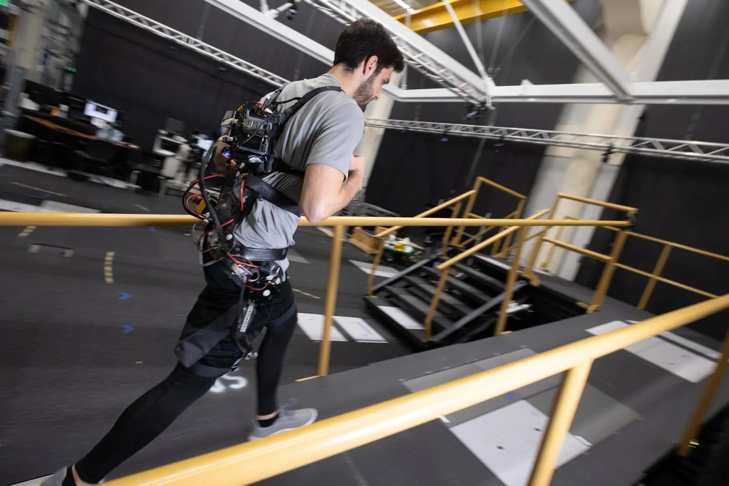 Dean Molinaro walks up a height-adjustable ramp, left, and similarly adjustable stairs, right, while wearing an experimental exoskeleton.
