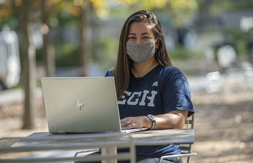 Georgia Tech Student with a laptop on a campus bench