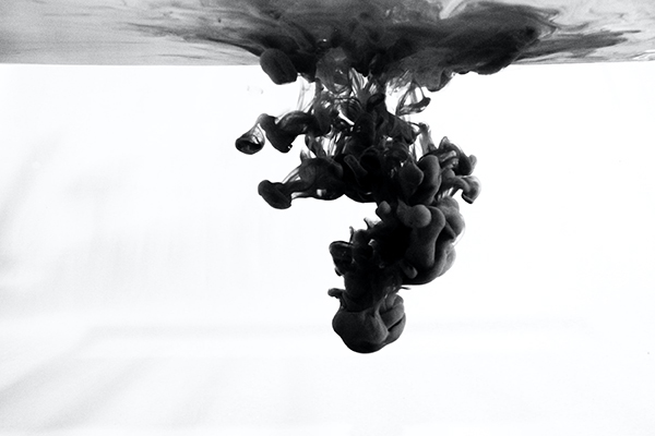 Black and white image of droplets of dark dye diffusing into water