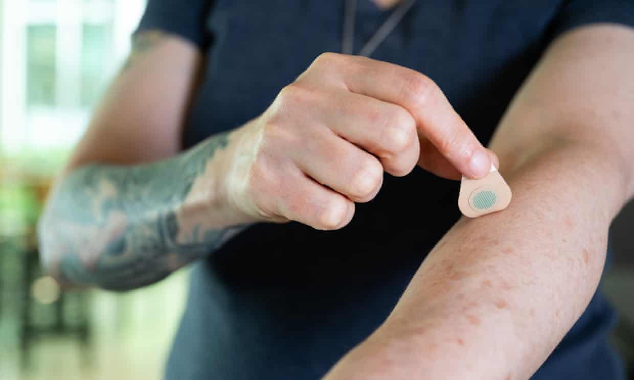 A person applying a microneedle tattoo patch to their own arm