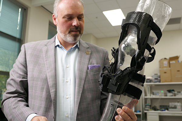 Omer Inan holding a device that tracks swelling and tissue damage in joints.