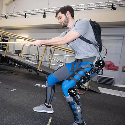 young male wearing an exoskelton device on his leg and pulling on a rope