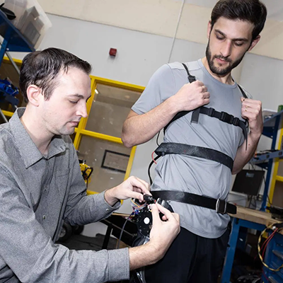 male researcher adjusting an exoskeleton on a male test subject
