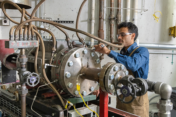 Researcher in a combustion lab installing an igniter on a high pressure combustion test rig.
