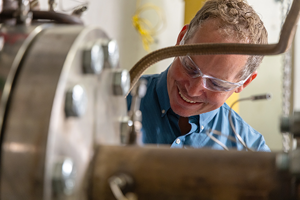 Benjamin Emerson inspecting a high pressure combustion test rig in a combustion lab at Georgia Tech.