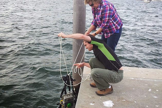 two people on a dock pulling an object out of the water