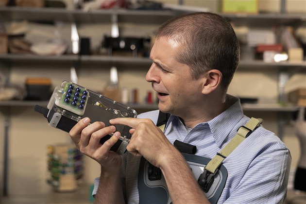 man in a light blue shirt with his head turned to the left looking at a rectangular object