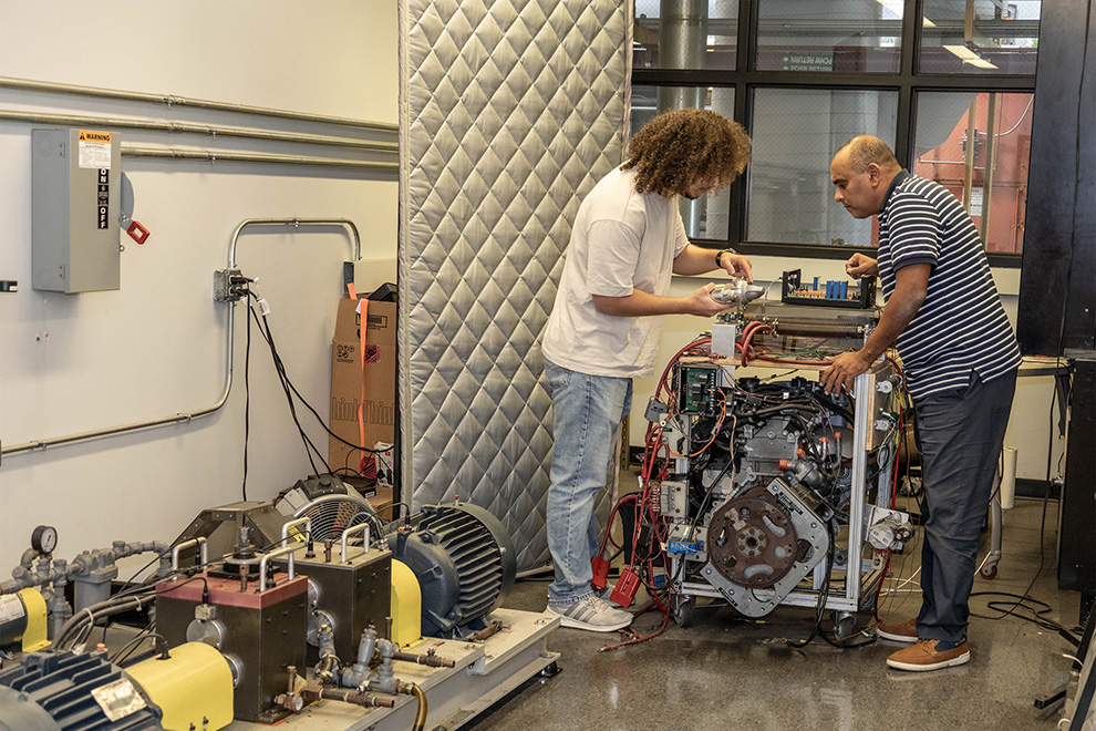 Two engineers examine equipment in a research lab, collaborating on testing and troubleshooting an industrial system..