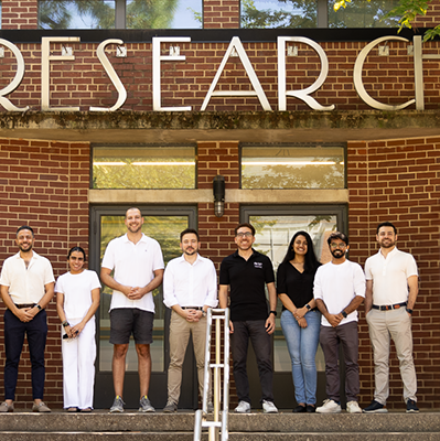 group photo of researchers standing in front of a brick building