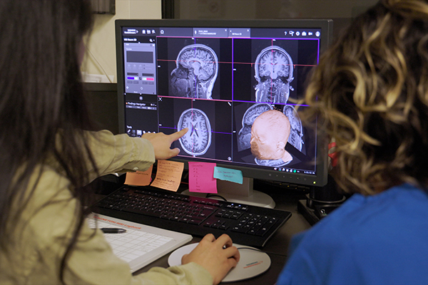 Yiren Ren and another researcher looking at a computer with data about the brain's response to listening to music.