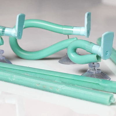 Green curved tubing and plastic components attached to suction cups on a white surface.


