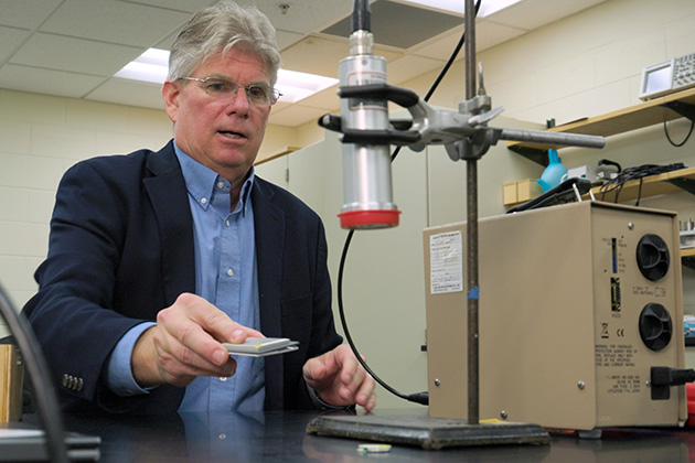Person seated at a laboratory bench operating scientific equipment.