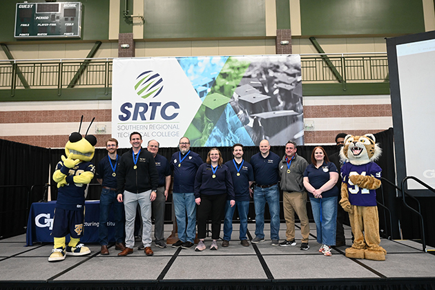 A group of event participants and mascots standing on a stage at Southern Regional Technical College in front of an SRTC banner.