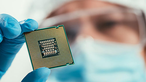close up of a man in lab attire holding a microchip while examining it