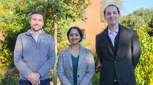two males with a female in the middle standing on the Georgia Tech campus with trees and a building in the background