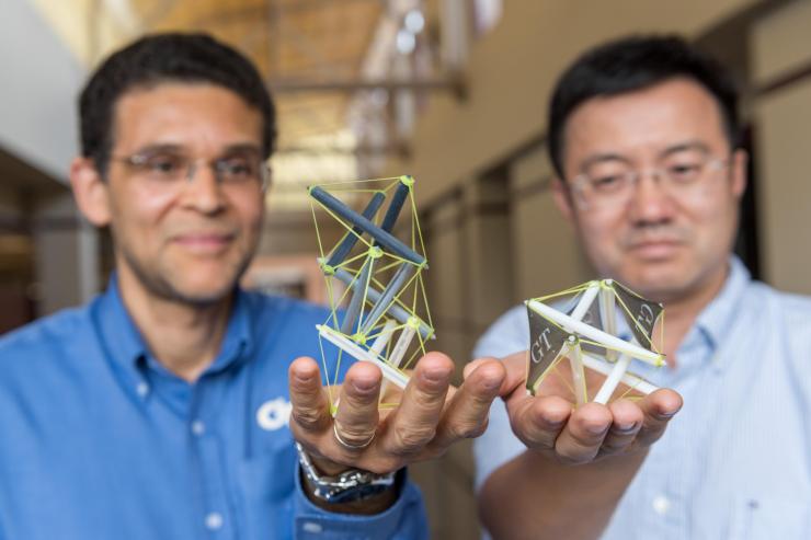 <p>Glaucio Paulino, a professor in Georgia Tech’s School of Civil and Environmental Engineering, and Jerry Qi, a professor in the George W. Woodruff School of Mechanical Engineering at Georgia Tech, hold objects 3-D printed that use tensegrity, a structural system of floating rods in compression and cables in continuous tension. (Credit: Rob Felt)</p>
