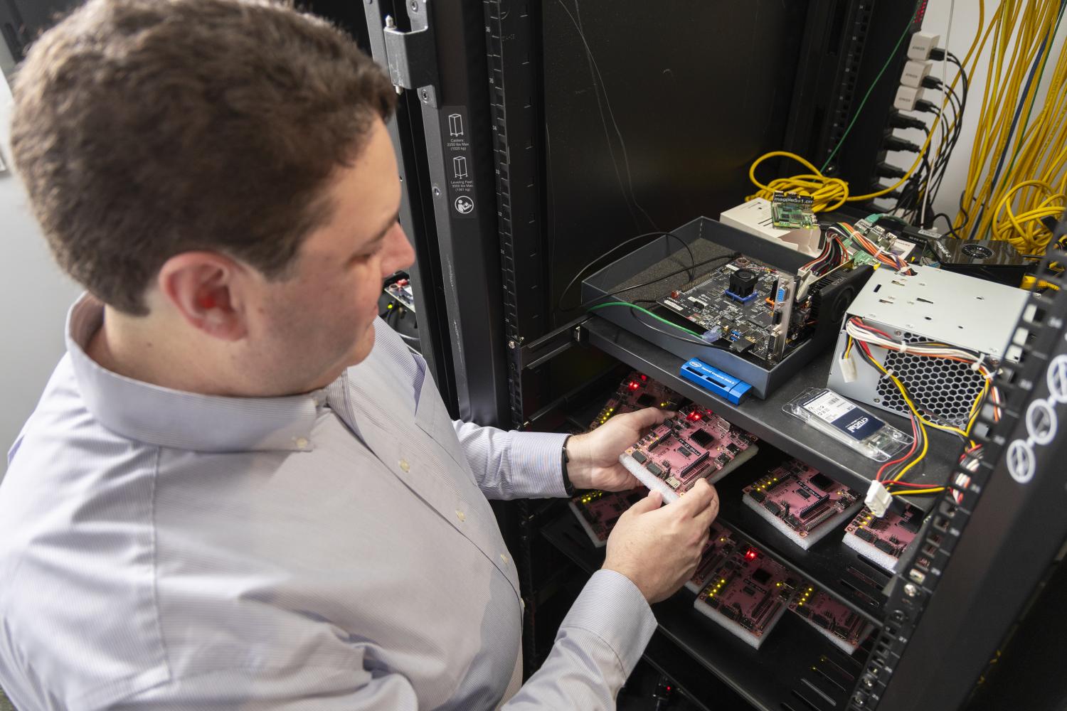A man holds a PYNQ-Z2 development boards used for FPGA (Field-Programmable Gate Array) development. 