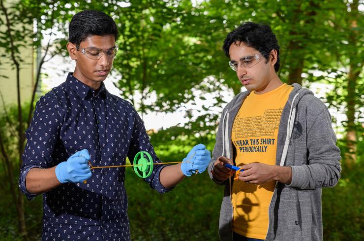 <p>Gaurav Byagathvalli, a senior at Lambert High School in Forsyth County, Georgia, demonstrates an inexpensive centrifuge created with a 3D printing process. M. Saad Bhamla, a Georgia Tech assistant professor, observes the device, which can be part of a "lab in a backpack." (Photo: Rob Felt, Georgia Tech)</p>