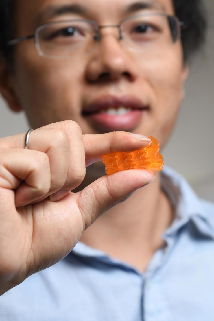 <p>Georgia Tech postdoctoral fellow Xiao Kuang demonstrates the compressibility of origami structures created through Digital Light Processing 3D printing. (Credit: Christopher Moore, Georgia Tech).</p>