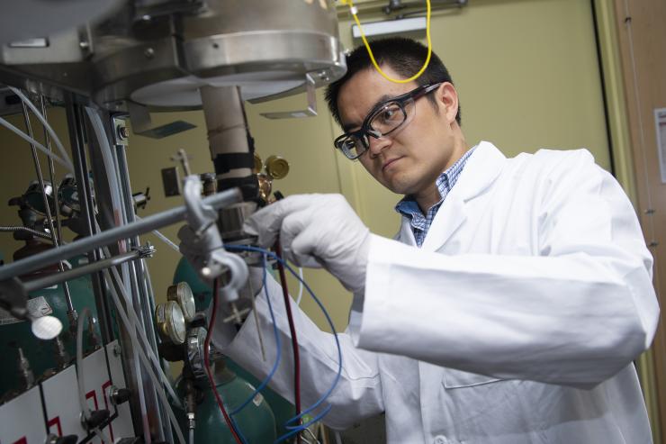 <p>Postdoctoral researcher Yu Chen sets up the new fuel cell in a unit used to test it in Meilin Liu's lab at Georgia Tech. Credit: Georgia Tech / Christopher Moore</p>