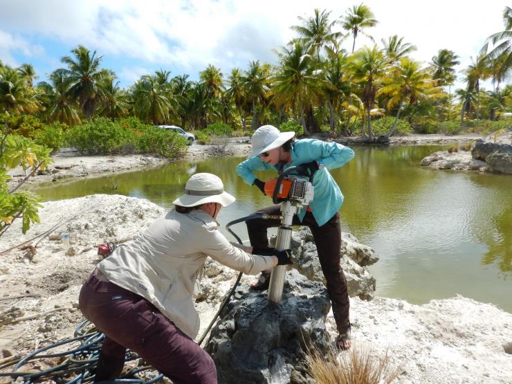 <p>Pam Grothe and Alyssa Atwood drill into a 5,000-year-old coral fossil on Kiritimati Island. Credit: Georgia Tech / Grothe / Cobb lab</p>