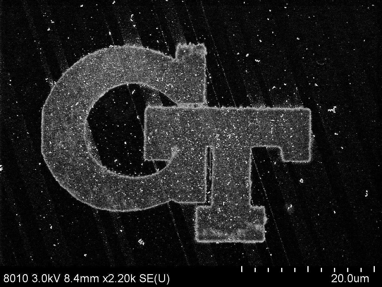 The Georgia Tech logo on a black background under a microscope