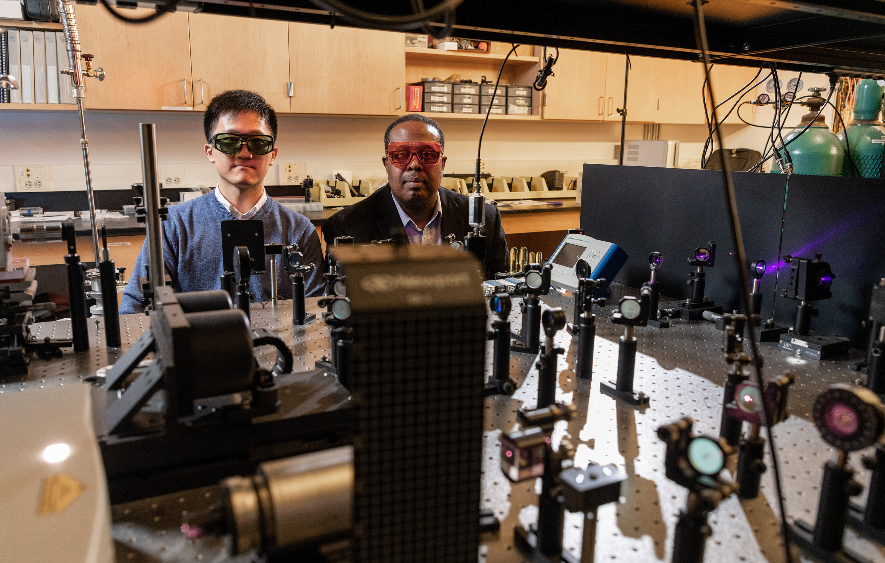 Researchers Cheng Zhe and Samuel Graham shown with an optical test setup for studying gallium nitride devices cooled by placement on a diamond substrate. (Credit: Rob Felt, Georgia Tech)
