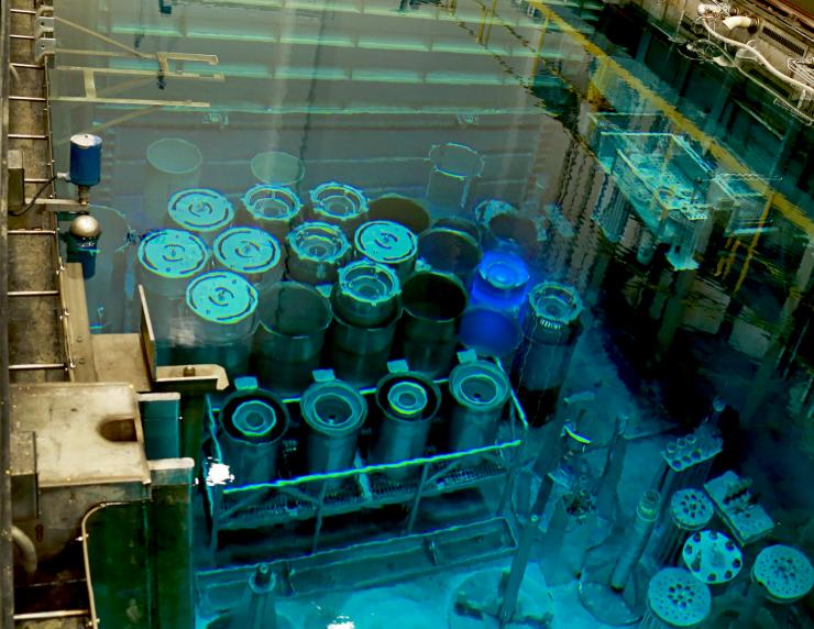 <p>Operating at 85 MW, an average fuel cycle for the HFIR at Oak Ridge National Laboratory generally runs for approximately 26 days. While submersed, the spent fuel emits a luminescent blue glow due to Cherenkov radiation, in which shedding electrons move through the water faster than the speed of light in water. Once removed from the reactor, spent fuel is then relocated into an adjacent holding pool for interim storage. Caption: ORNL Photo credit: Jason Richards/ORNL</p>