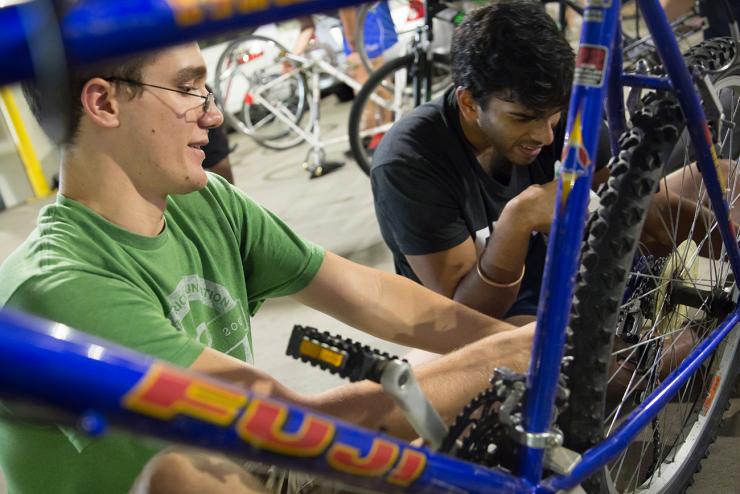 <p>Joseph Robinson (left), an aerospace engineering student, and Arjun Chintapalli, a mechanical engineering student, work on a bike at Starter Bikes in the Campus Recreation Center parking garage. </p>