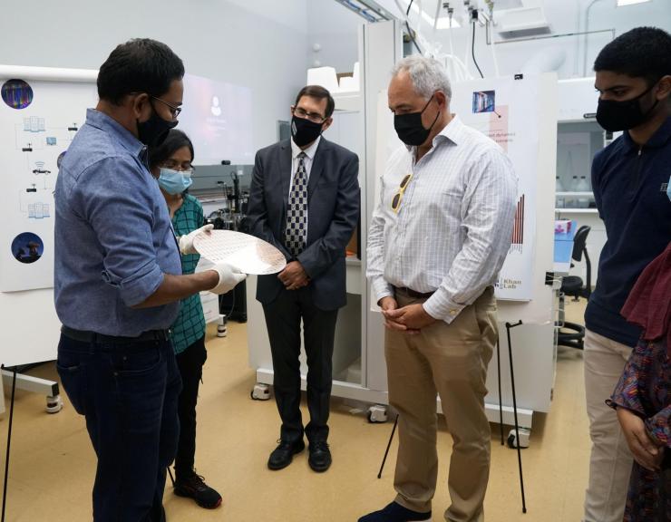 <p>Asif Khan (left) shows President Ángel Cabrera a 300 nm FEFET wafer that his lab received from Global Foundries. Pictured left to right are Khan, Nujhat Tasneem, Douglas Blough, Cabrera, and Prasanna Ravindran.</p>