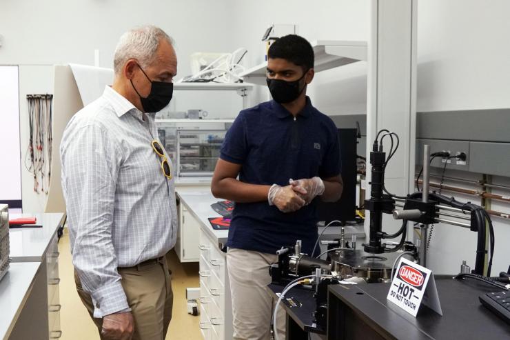 <p>Prasanna Ravindran (right) shows President Ángel Cabrera his cryogenic measurement set up which can measure devices down to 4 K.</p>