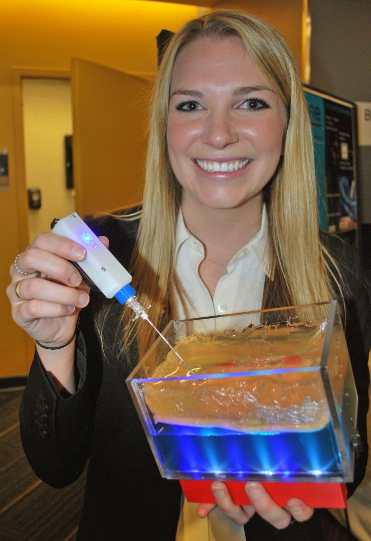 <p>Marci Medford demonstrates the device her Capstone team developed.</p>