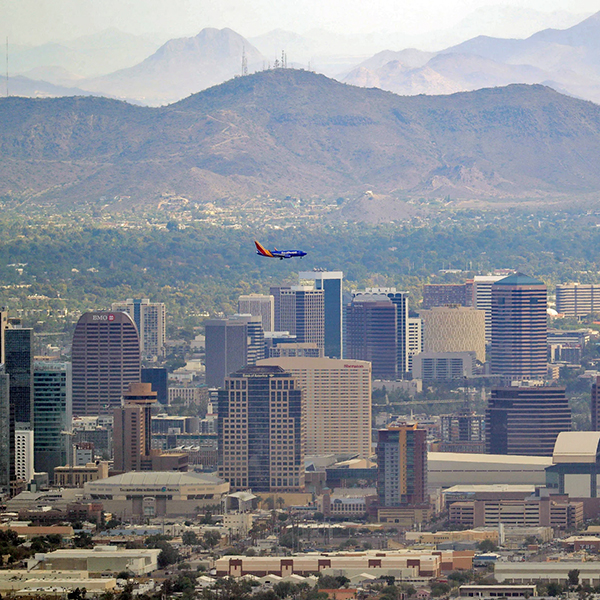 A view of Phoenix, Arizona with downtown, South Mountain, and a Southwest Airlines jet in frame.