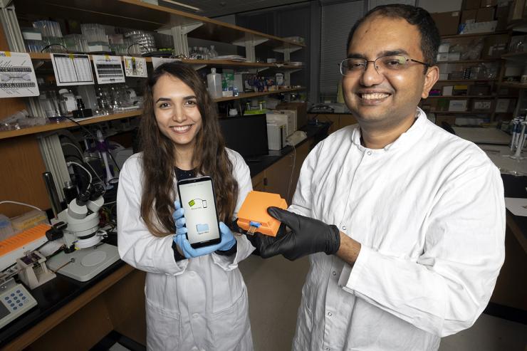 <p>Postdoctoral fellow Neda Rafat and Assistant Professor Aniruddh Sarkar with the Bluetooth reader and smartphone app their team developed to display test results from a new electronic Covid-19 test chip. (Photo: Candler Hobbs)</p>