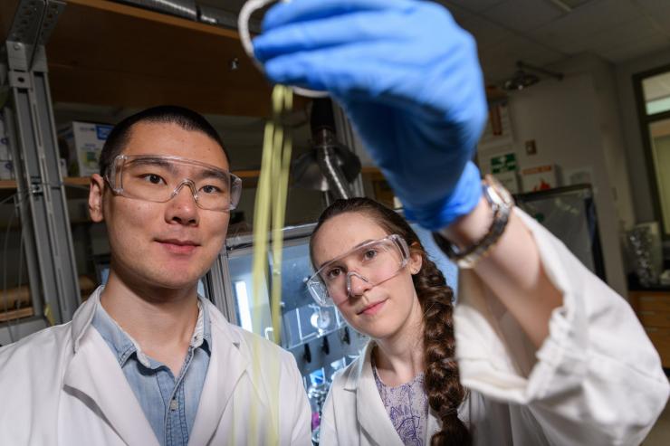 <p>Fengyi Zhang and Emily K. McGuinness, graduate students at Georgia Tech, inspect a hollow fiber membrane that can be used for low-energy chemical separation. (Credit: Rob Felt)</p>