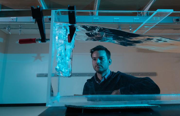 <p>The study's principal investigator Alex Robel observes ice fracture patterns caused by wavy water in a test tank at his lab at Georgia Tech. Credit: Georgia Tech / Allison Carter</p>