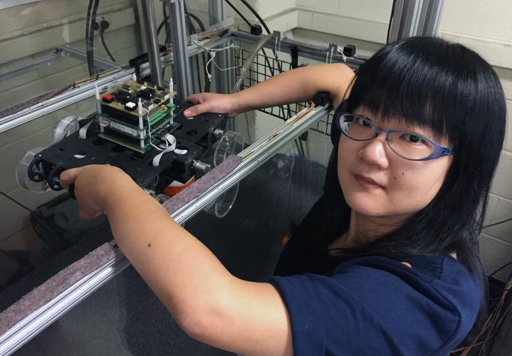<p>Georgia Tech graduate student Feifei Qian prepares to place Sandbot, a bio-inspired hexapedal robot, into a trackway filled with granular media. The robot was used to study how the stiffness of a loosely-packed surface affects the ability to move across it. (Credit: John Toon, Georgia Tech)</p>