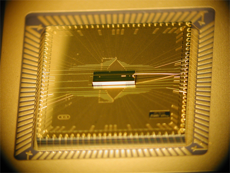 <p>Photograph shows the completed BGA trap assembly. The trap chip is at the center, sitting atop the larger interposer chip that fans out the wiring. The trap chip surface area is 1 millimeter by 3 millimeters, while the interposer is roughly 1 centimeter square. (Credit: D. Youngner, Honeywell)</p>