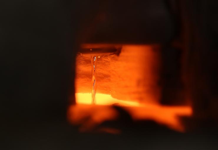 <p>This image shows liquid metal flowing at 1400 degrees Celsius in the laboratory of Asegun Henry at Georgia Tech. Even though all the surrounding materials are glowing, the tin remains reflective and the ripples from the pool of tin below are visible via reflections from the stream. (Credit: Caleb Amy)</p>