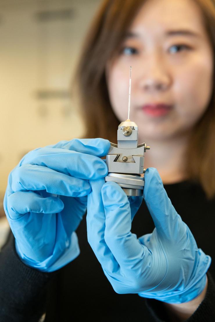 <p>Georgia Tech graduate research assistant Xuetian Ma holds a reaction vessel similar to those used in the research on nanoscale crystalline growth. The vessels were made of a high-strength quartz tube about a millimeter in diameter and about two inches long. (Credit: Allison Carter, Georgia Tech)</p>