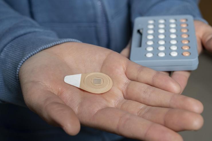 <p>An experimental microneedle patch is shown next to a blister pack of birth control pills. Designed to be self-administered by women for long-acting contraception, the patch could provide a new family planning option. (Credit: Christopher Moore, Georgia Tech)</p>