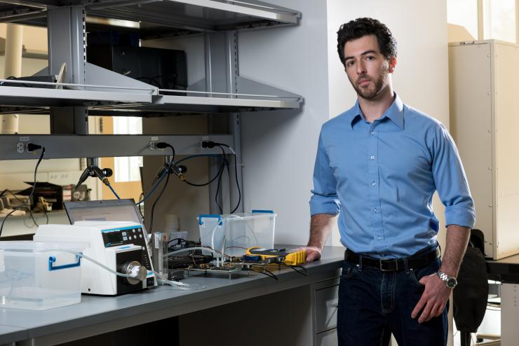 <p>Georgia Tech graduate student Tom Sarvey is shown with test equipment used to compare the performance of stock FPGA devices, one with experimental liquid cooling and the other using stock air cooling. (Credit: Rob Felt, Georgia Tech)</p>