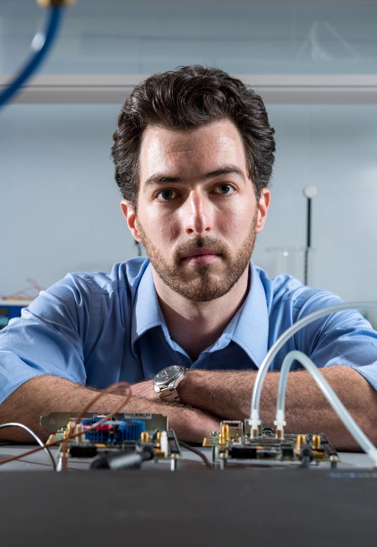 <p>Georgia Tech graduate student Tom Sarvey is shown with test equipment used to compare the performance of stock FPGA devices, one with experimental liquid cooling and the other using stock air cooling. (Credit: Rob Felt, Georgia Tech)</p>