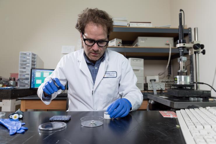 <p>Georgia Tech postdoctoral researcher Isaac Gállego prepares a sample DNA nanostructure for imaging in an atomic force microscope. (Credit: Rob Felt)</p>