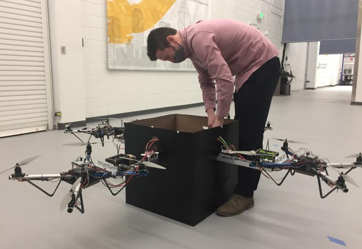<p>Graduate student Kevin Webb adjusts the control system used to coordinate the activity of four drones to lift the package. (Credit: John Toon, Georgia Tech)</p>