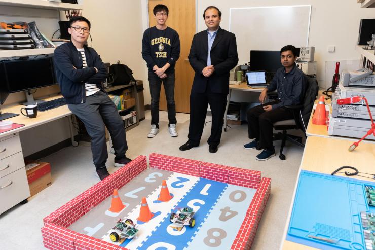<p>Georgia Tech Researchers Ningyuan Cao, Muya Chang, Arijit Raychowdhury and Anupam Golder with a laboratory demonstration of an ultra-low power hybrid chip driving two small robotic cars. (Photo: Allison Carter, Georgia Tech)</p>