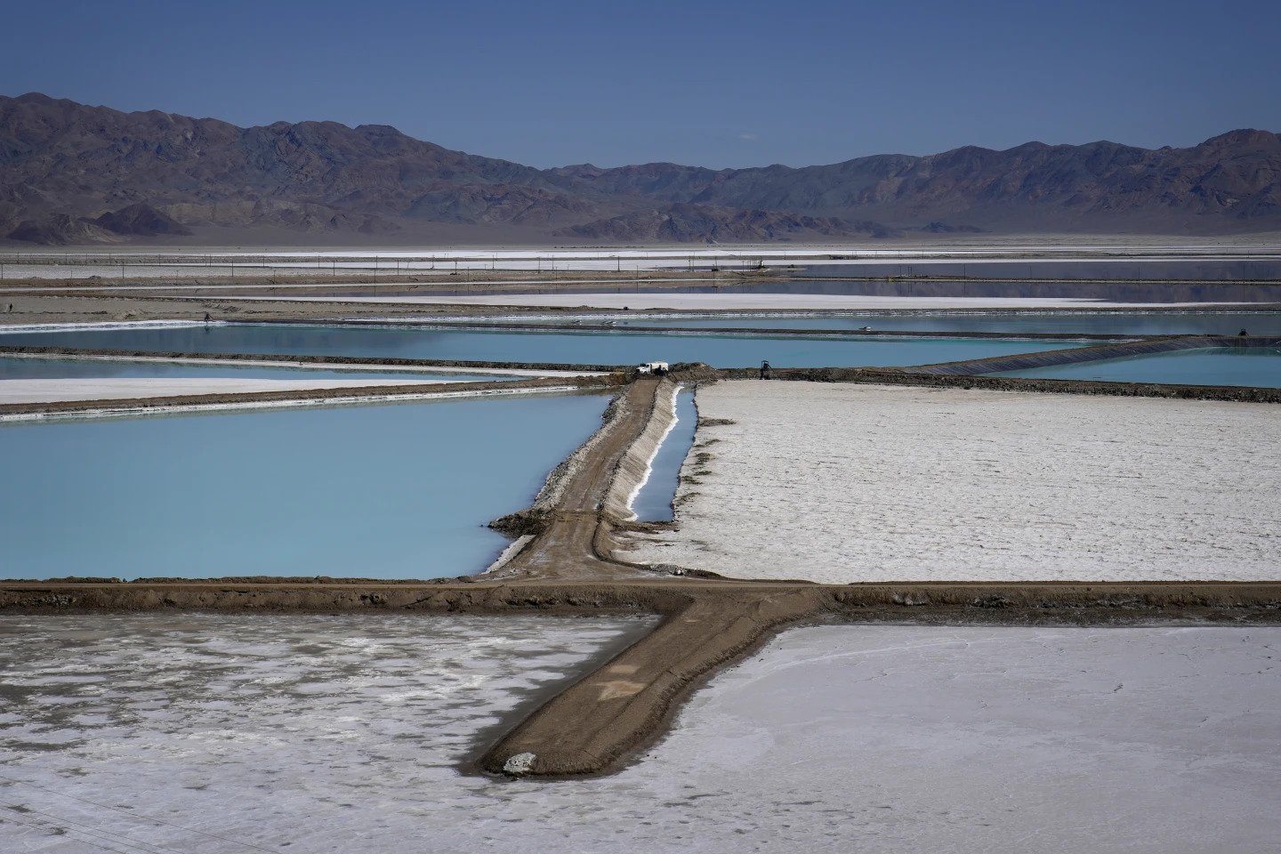 A truck is parked betwenn brine evaporation ponds at Albemarle Corp's Silver Peak lithium facility, Oct 6, 2022, in Silver Peeak, Nev. The Energy Department is making a push to strenghten the U.S. battery supply chain, announcing Wednesday, Nov 15, 2023, up to $3.5 billion for companies that produce batteries and the critical minerals that go into them. (AP Photo/John Locher, File)