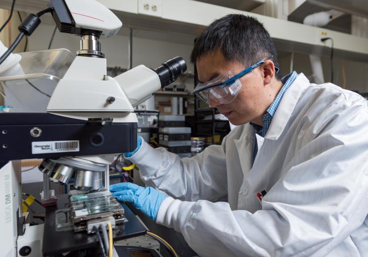 <p>Georgia Tech Research Scientist Ming He adjusts the equipment for the meniscus-assisted solution printing (MASP) technique used to fabricate perovskite films for solar cells. (Credit: Rob Felt, Georgia Tech)</p>