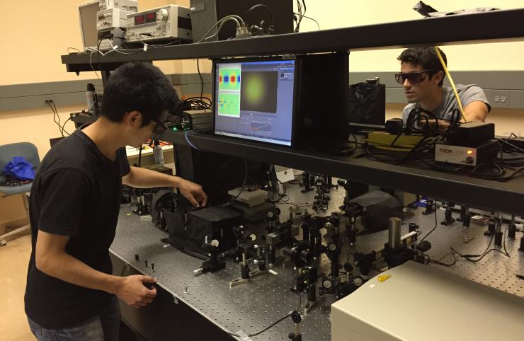 <p>Georgia Tech researchers (left to right) Shoufeng Lan and Sean Rodrigues adjust optical equipment used to measure the properties of a new metamaterial waveguide. A Georgia Tech research team reported on the creation of a nonlinear material that has opposite refractive indices at the fundamental and harmonic frequencies of light. (Credit: John Toon, Georgia Tech)</p>
