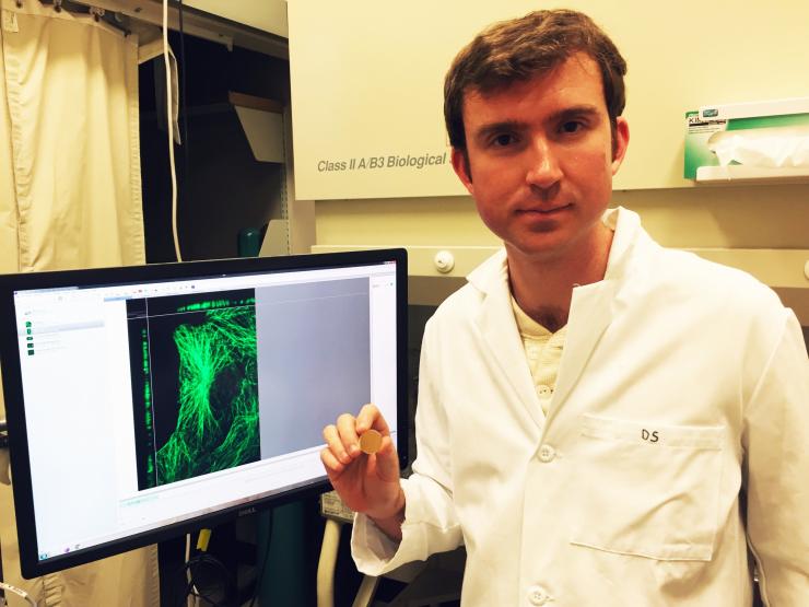 <p>Eric Alonas, a Georgia Tech graduate student, holds an example of the type of mirror that the researchers used to increase the resolution of super-resolution microscopes for examining cells. (Credit: John Toon, Georgia Tech)</p>